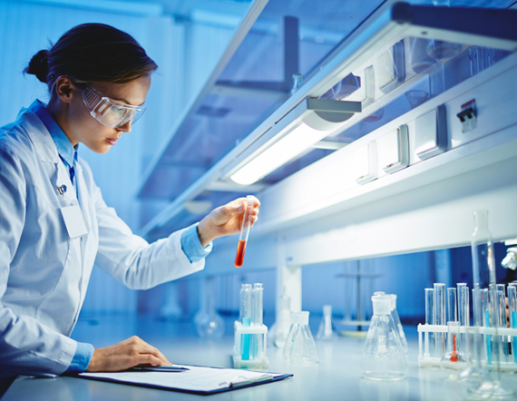 Chemist in laboratory examining a test tube of red liquid