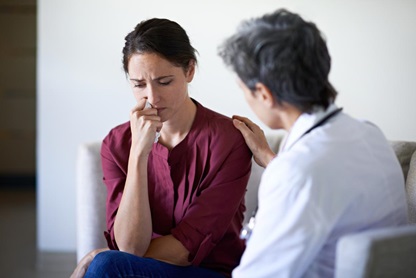 Doctor consoling with a hand on the shoulder of a distraught female patient