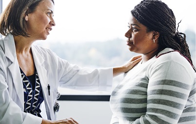 Doctor reaching out with a hand on the shoulder to reassure a concerned patient