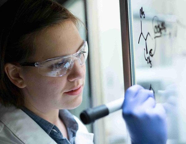 Scientist writing on glass wall