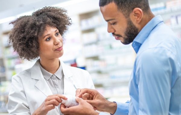 Woman pharmacist speaking with customer about medication bottle.